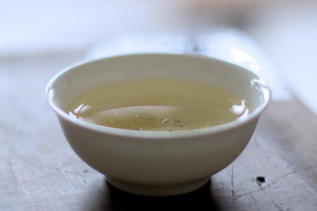 porcelain tea cup on wooden table filled with wild farmed loose leaf tea