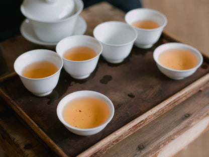 white porcelain cups on a wooden board filled with naturally farmed Dong Ding oolong tea