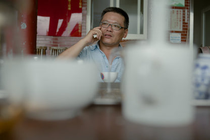 farmer sitting behind table drinking naturally farmed tea