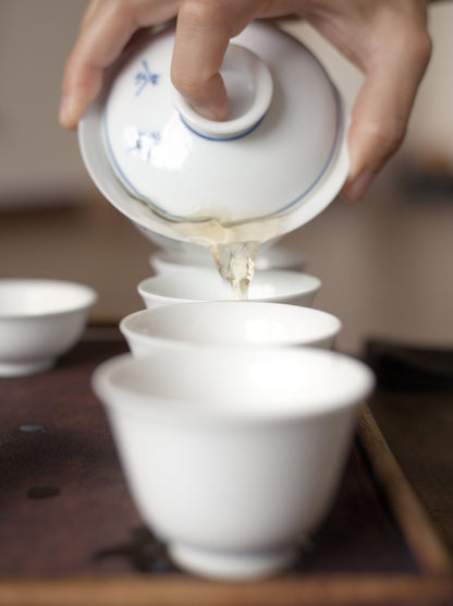 pouring naturally farmed Tieguanyin oolong tea from gaiwan into white porcelain cups