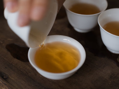 pouring naturally farmed oolong tea into white porcelain cup