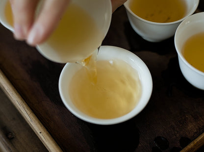 pouring naturally farmed oolong tea into white porcelain cup