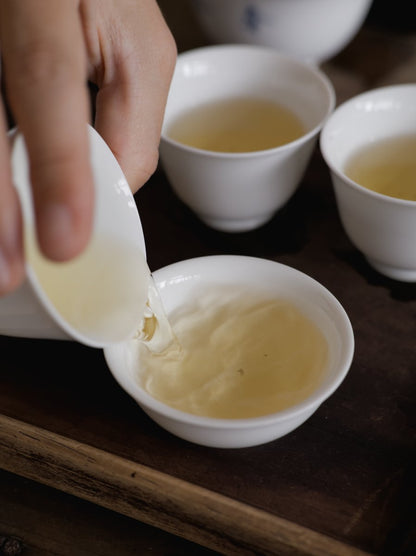 pouring naturally farmed oolong tea into white porcelain cup