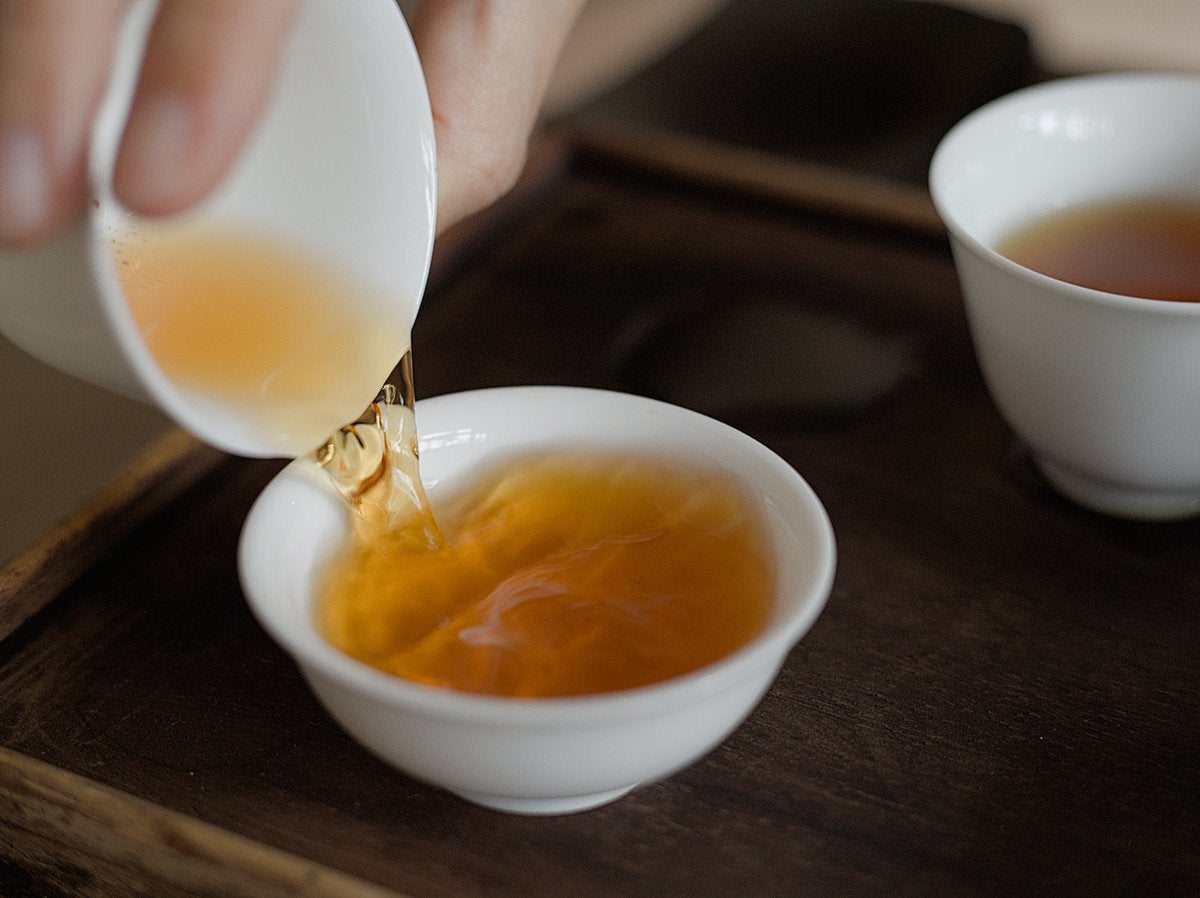 pouring naturally farmed red oolong tea in to white porcelain cup