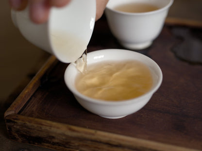 pouring naturally farmed Tieguanyin oolong tea into white porcelain cup