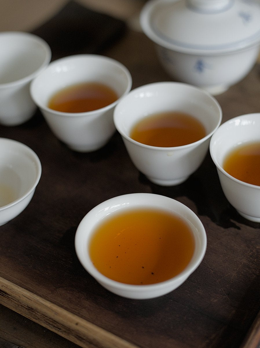 white porcelain cups on a wooden board filled with naturally farmed red oolong tea