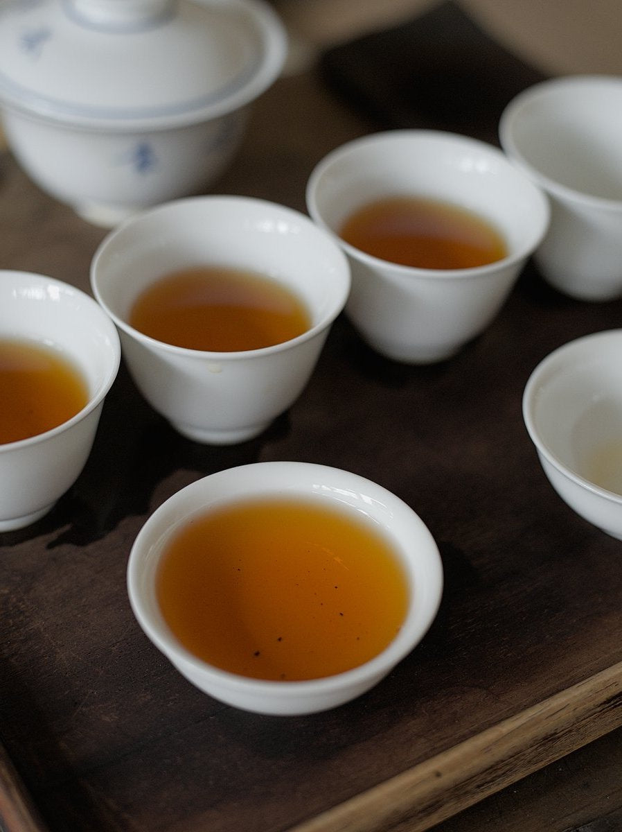 white porcelain cups on wooden board filled with naturally farmed red oolong tea