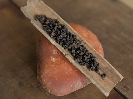 naturally farmed red oolong tea sitting on wooden scoop on a rock