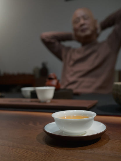 teacher Lai sitting behind dark wooden table brewing his charcoal roasted oolong tea